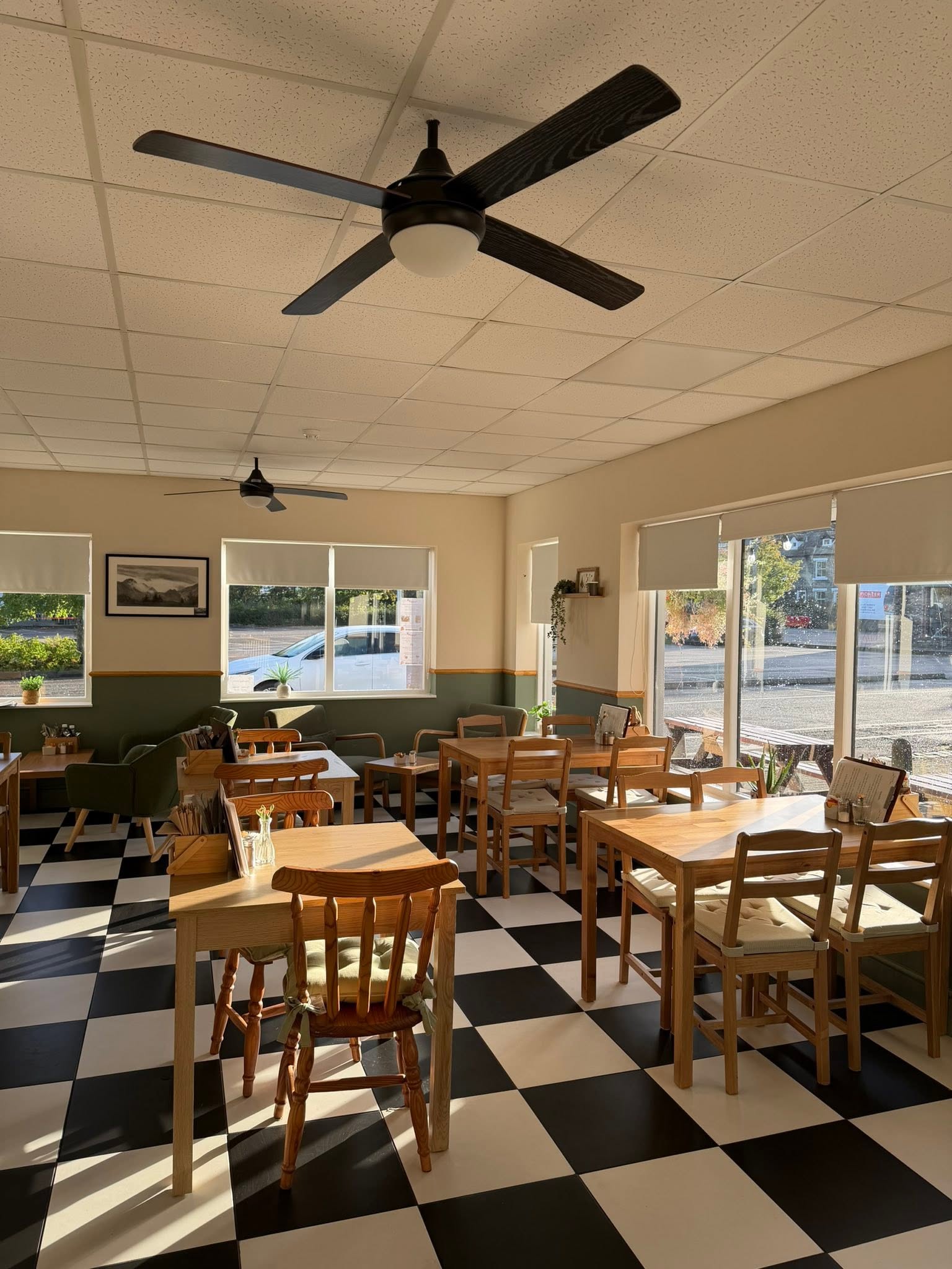 Nook’s sunlit dining room with wooden tables, green walls and a black-and-white floor